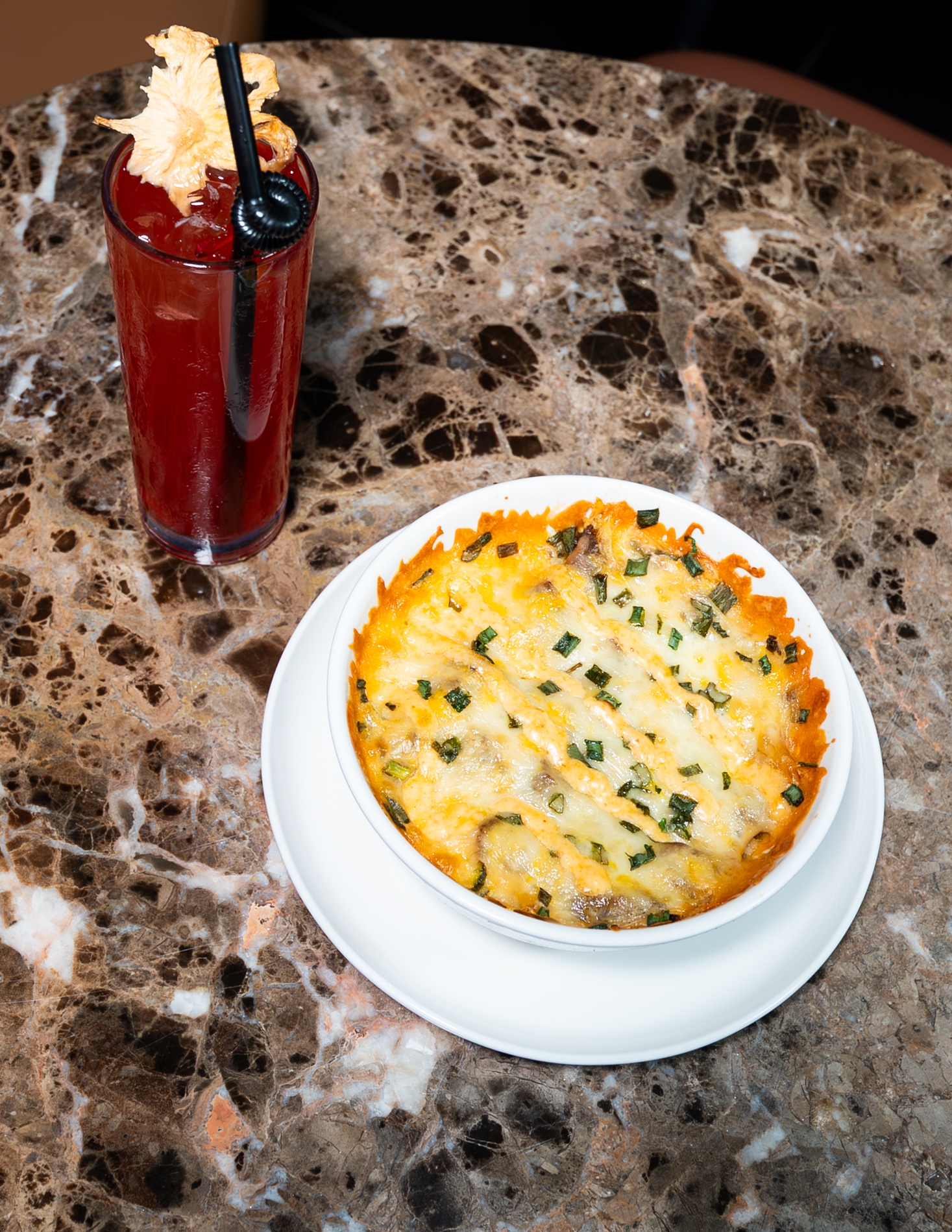 A cocktail and a cheesy bake on the table